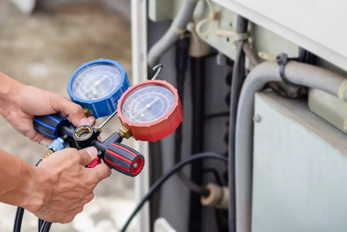 Technician reading refrigerant gauges on an AC system